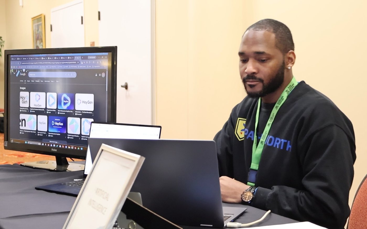 Jermaine Peguese working at a laptop beside a large monitor