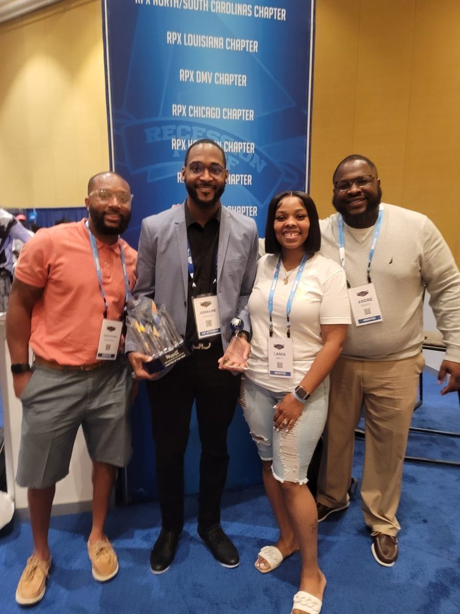 Jermaine holding a chapter award in front of the Recession Proof chapter-network banner.